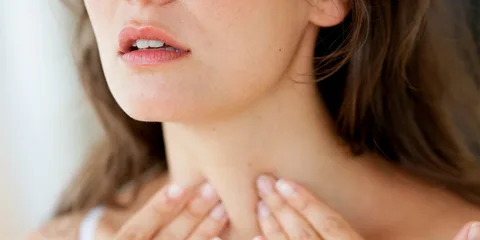 Mulher tocando a tireoide no pescoço